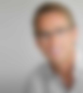 A blurry picture of a man with glasses