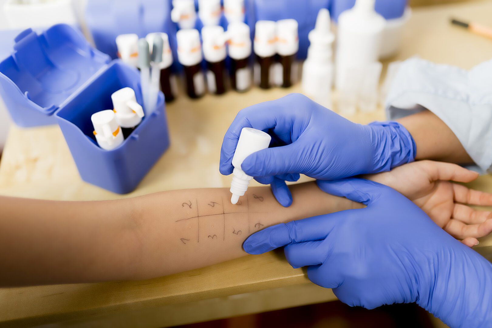 A person in blue gloves is painting something on the skin.