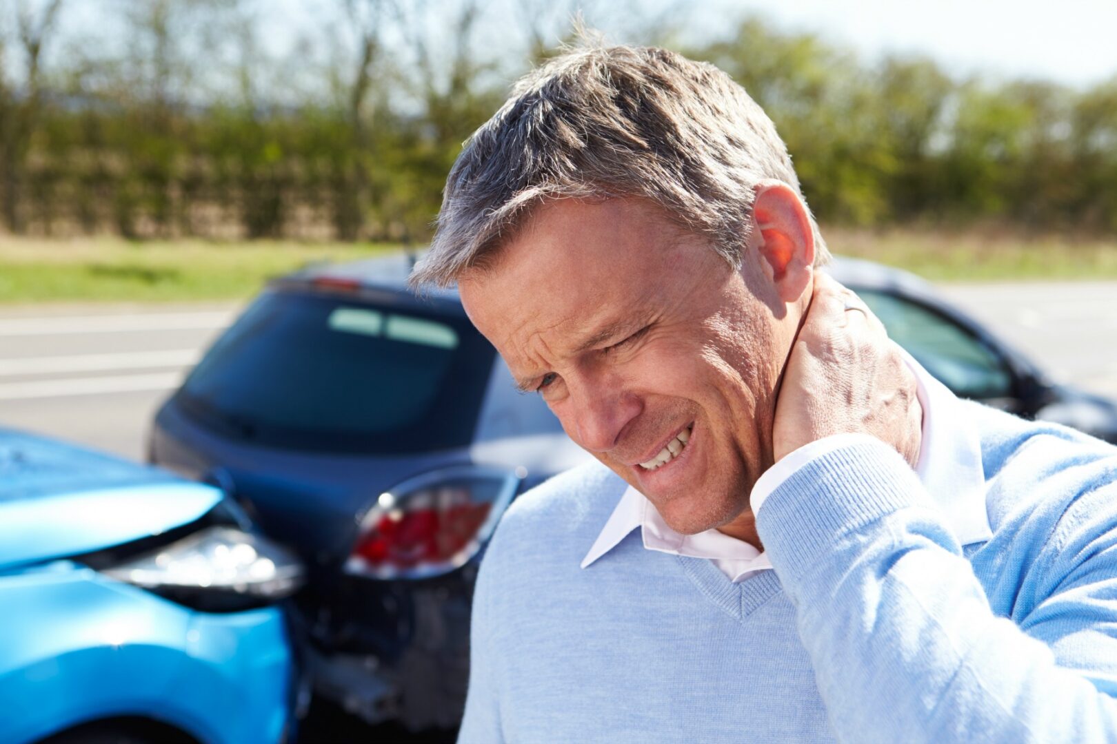 A man holding his neck in pain after an accident.