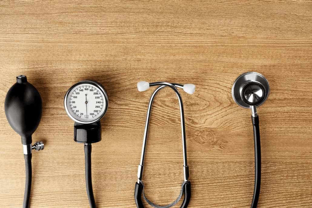 A stethoscope and blood pressure monitor on top of a wooden table.