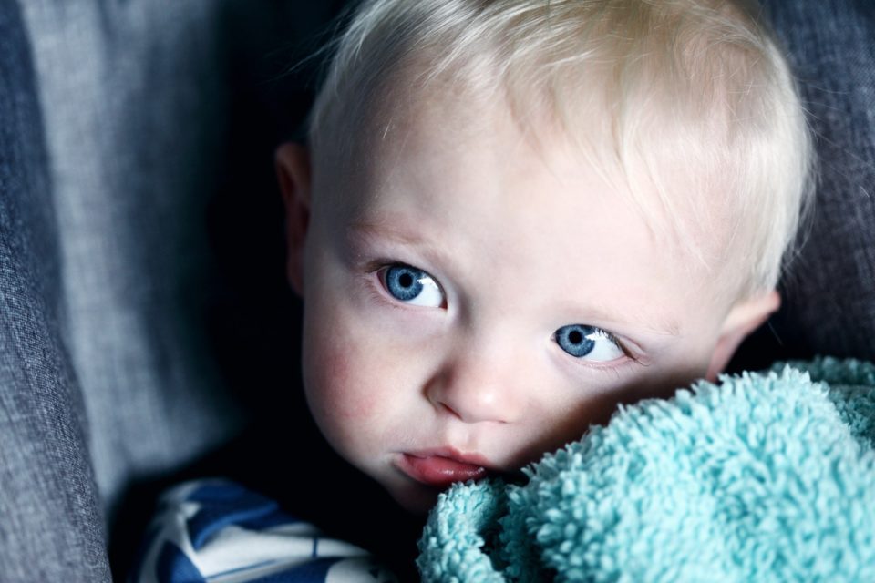 A baby is wrapped in a blanket and looking at the camera.