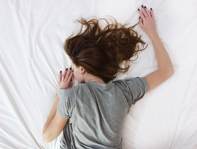 A woman laying in bed with her hair blowing.